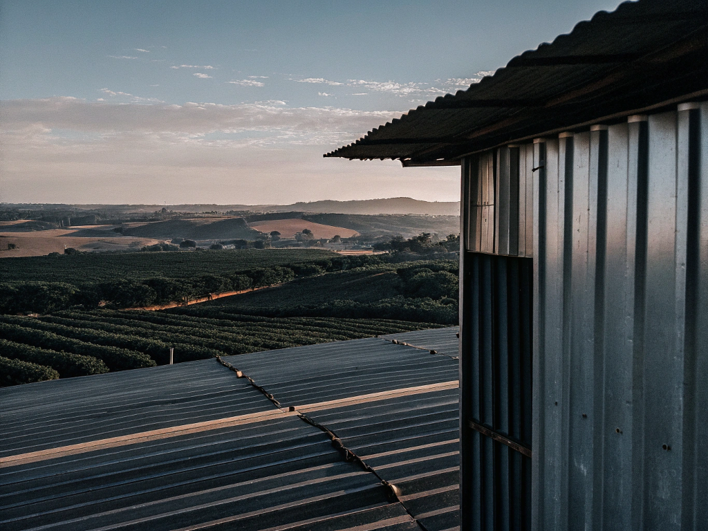 View over corrugated metal roofs onto coffee fields and rolling hills in Norte de Minas.