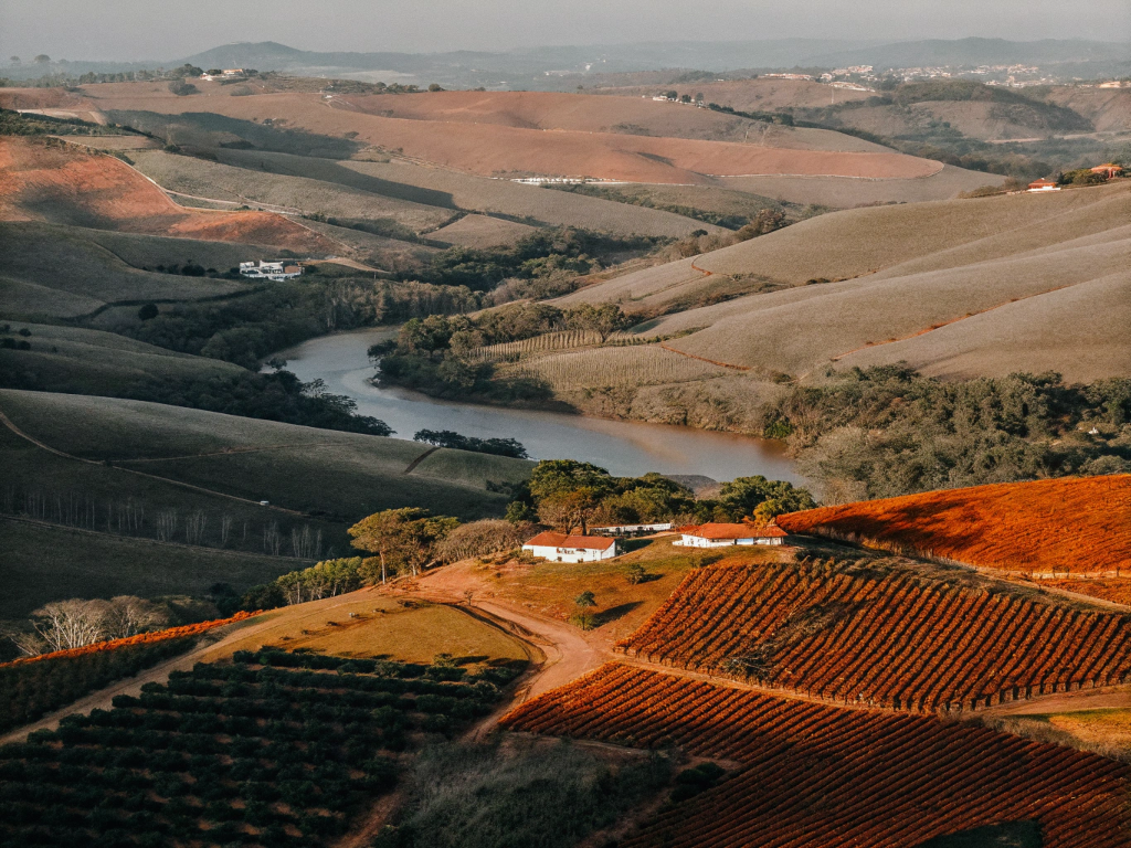 Aerial view of the Vale do Mucuri with a river and coffee plantations on rolling hills.