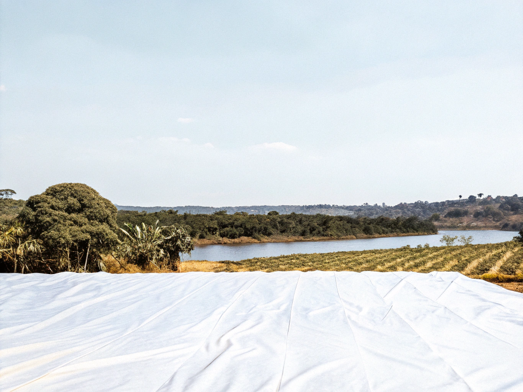 Coffee drying tarp overlooking a river and plantations in Vale do Rio Doce.
